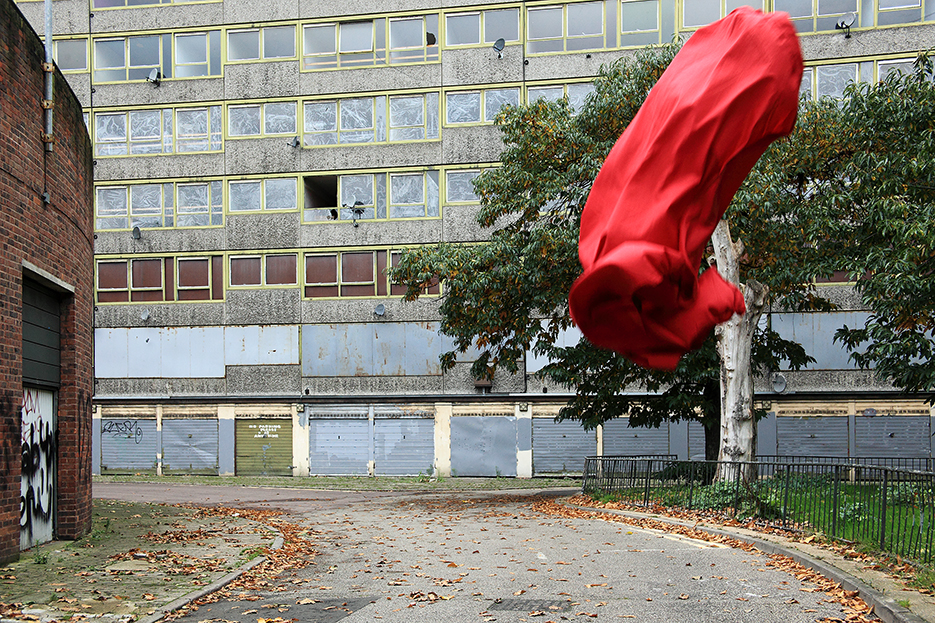 abandoned social housing block in London, a red cloth is flying in the wind infront of the building, shaped like a penis