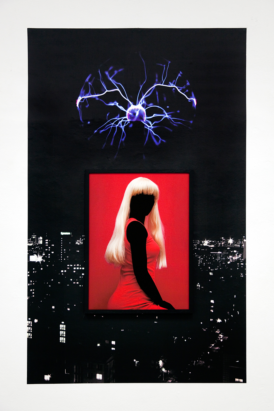 installationview - deatial befangen: a woman in a red dress with a blond wig and erased skin hangs framed on top  large pasted landsape of berlins cittyskyline at night with a plasmaball floating in the air